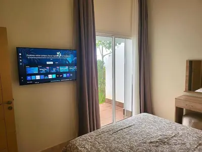 a bedroom with a bed and a television on the wall at Bouznika Apartement de luxe 2 Chambres RDC in Bouznika