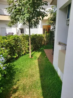 a tree in the grass next to a building at Bouznika Apartement de luxe 2 Chambres RDC in Bouznika