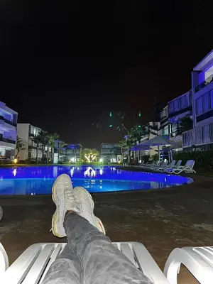 a person laying on a bench near a swimming pool at night at Blanca beach in Sidi Rahal