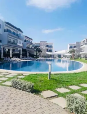 a swimming pool in front of some buildings at Blanca beach in Sidi Rahal