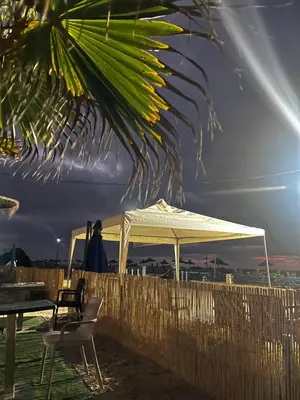 a white tent on the beach with a table and chairs at Blanca beach in Sidi Rahal