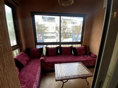 a living room with a red couch and a window at Appartement a louer a mansouria rico flores in O Ben Slimane