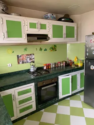 a kitchen with green and white cabinets and a refrigerator at Résidence sara in Casablanca