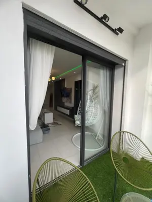 a sliding glass door with chairs and a living room at Luxueux appartement a harhoura près de la mer in Temara