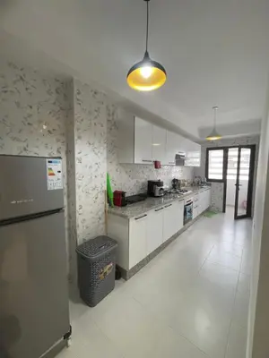 a kitchen with white cabinets and a refrigerator at Luxueux appartement a harhoura près de la mer in Temara