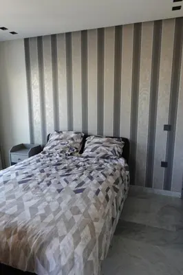 a bed in a bedroom with a striped wall at Calm and lovely appartement well located in Casablanca