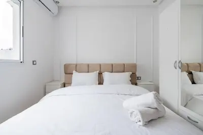 a white bedroom with a large bed and a mirror at TT Holidays Centro in Rabat