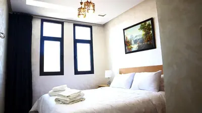 a bedroom with a white bed with two windows at Beautiful and cosy apartment in Casablanca