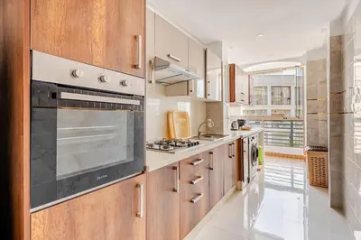 a kitchen with wooden cabinets and a stove top oven at Grand Appartement de standing sécurisé, proche plage avec piscine privée in Bouznika