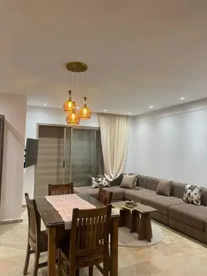 a living room with a couch and a table at Appartement vu sur piscine à 5 minutes de la plage in Mansouria