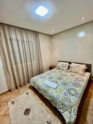 a bedroom with a bed with a comforter and a window at Appartement de Luxe - Piscine et Accès à la Plage in El Harhoura