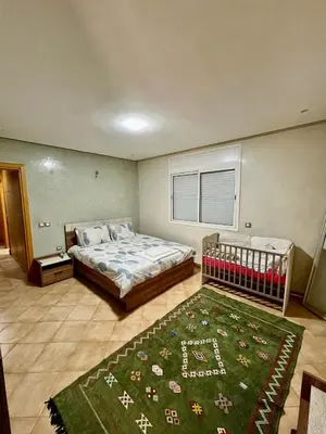a bedroom with a bed and a green rug at Appartement de Luxe - Piscine et Accès à la Plage in El Harhoura