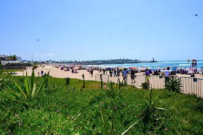a group of people on a beach with umbrellas at Appartement de Luxe - Piscine et Accès à la Plage in El Harhoura