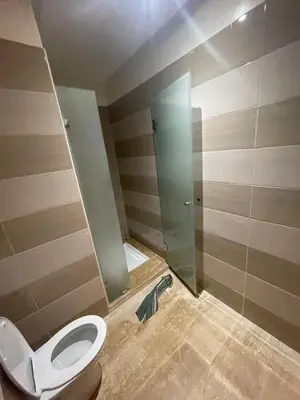 a bathroom with a toilet and a glass shower stall at Rabat en face de océan in Rabat