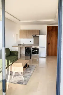 a living room with a green couch and a kitchen at Tour 33 CFC Studio moderne & raffiné en plein cœur de Casa in Casablanca