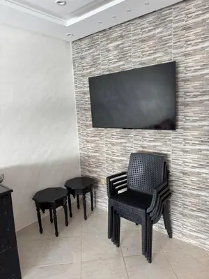 a room with three chairs and a television on a brick wall at Résidence oasis beach mansouriah in Mohammedia