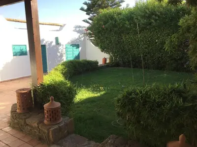 a garden with a yard with grass and trees at beachfront house frond de mer in Skhirat