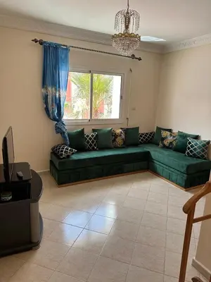 a living room with a green couch and a window at Ryad chaouia in Dar Mohammed Ould Haj Jilali
