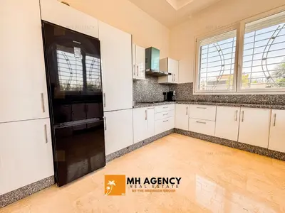 a kitchen with white cabinets and a black refrigerator at Oliveraie - Villa Benslimane in O Ben Slimane