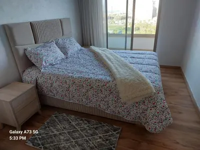 a bedroom with a bed with a blue blanket and a window at appartement à Zenata casablanca in Aïn Harrouda