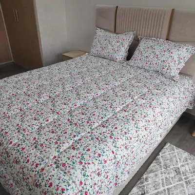 a bed with a floral comforter and two pillows at appartement à Zenata casablanca in Aïn Harrouda