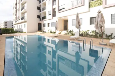 a swimming pool in front of a building at Elegant Apartment with Pool & Moroccan Lounge in Bouznika