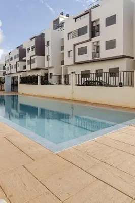 an empty swimming pool in front of a building at Elegant Apartment with Pool & Moroccan Lounge in Bouznika
