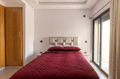 a bedroom with a large bed with red pillows at Elegant Apartment with Pool & Moroccan Lounge in Bouznika