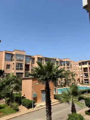 two palm trees in front of an apartment complex at Ricoflores Palm in O Ben Slimane