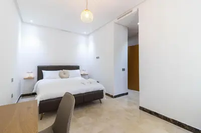 a bedroom with a bed and a table and chairs at Studio 1 Min Beach - Pool - Air conditioning - Fiber in Mohammedia