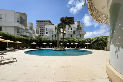 a swimming pool with chairs and umbrellas and buildings at Elegant Family Unit with Pool & Gym Casa Finance City m2a in Casablanca