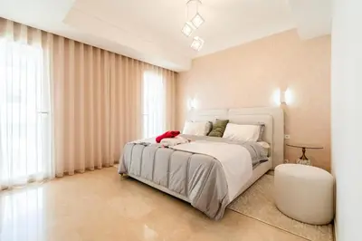 a bedroom with a white bed with a stuffed animal on it at Elegant Family Unit with Pool & Gym Casa Finance City m2a in Casablanca