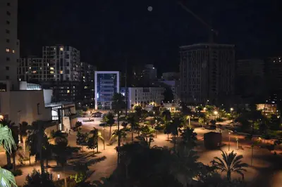 a city at night with palm trees and buildings at Kridarek - Appartement chic et cosy à Casa Finance City in Casablanca