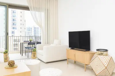 a white living room with a white couch and a tv at Kridarek - Appartement chic et cosy à Casa Finance City in Casablanca