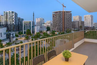 a balcony with a table and chairs and a city at Kridarek - Appartement chic et cosy à Casa Finance City in Casablanca