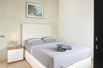 a white bedroom with two beds and a night stand at Kridarek - Bel appartement avec piscine à Dar Bouazza in Tamaris