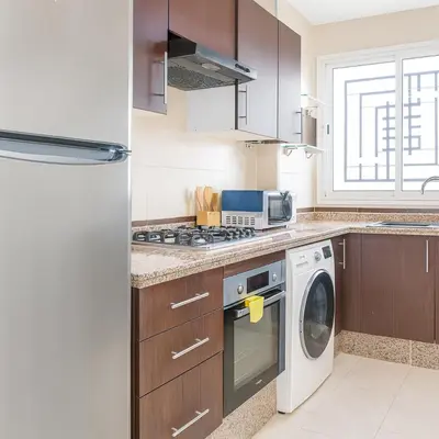 a kitchen with a stove top oven next to a dishwasher at Kridarek - Bel appartement avec piscine à Dar Bouazza in Tamaris