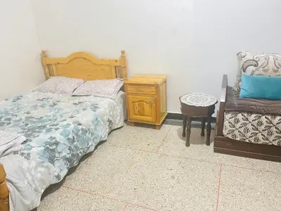 a bedroom with a bed and a table and a chair at Msn in Rabat
