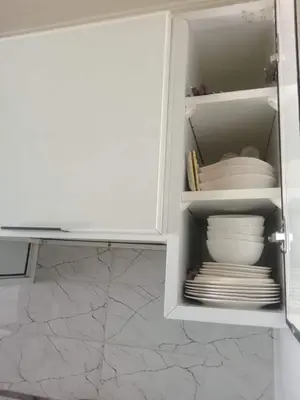 a white cabinet with plates and dishes in it at Appartement moderne et confortable proche plages in Casablanca