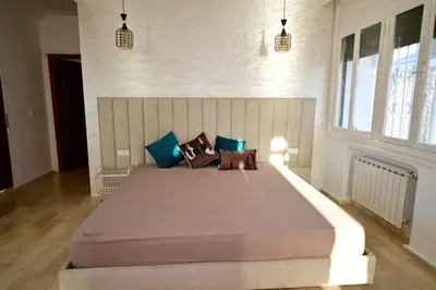a bedroom with a large bed with blue and brown pillows at The 5-Suite Beachfront Villa in O Ben Slimane