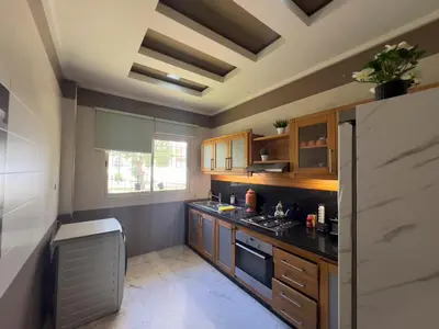 a kitchen with wooden cabinets and a black counter top at Family Apartment à Jnane California Confort & Proximité in Casablanca