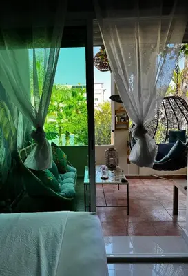 a room with a bed and two chairs and windows at High Standing Duplex - Pool Sun in Mohammedia