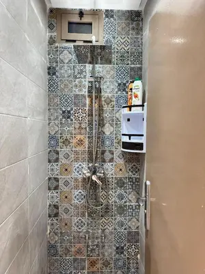 a shower in a bathroom with a tile wall at Appartement arome in Rabat