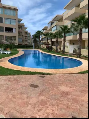 a large swimming pool in front of a building at Appartement vue à la mer Bouznika in Sidi el Haj Bou Derbala