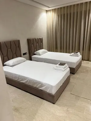 two beds in a hotel room with white sheets at Comfortable apartment in a gated community in Casablanca