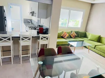 a living room with a green couch and a kitchen at Fal azure in Bouznika