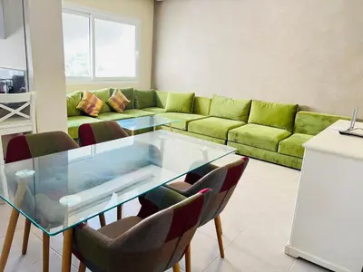 a living room with a glass table and a green couch at Fal azure in Bouznika