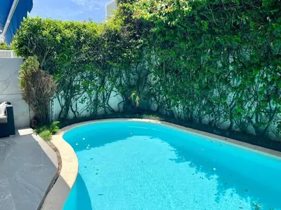 a swimming pool in front of a wall with trees at Charming villa in a coastal area in Casablanca