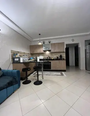 a living room with a blue couch and a kitchen at Garden beach 2 in Sidi Rahal