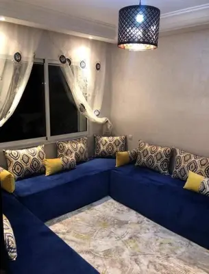 a blue couch with yellow pillows in a living room at Garden beach 2 in Sidi Rahal